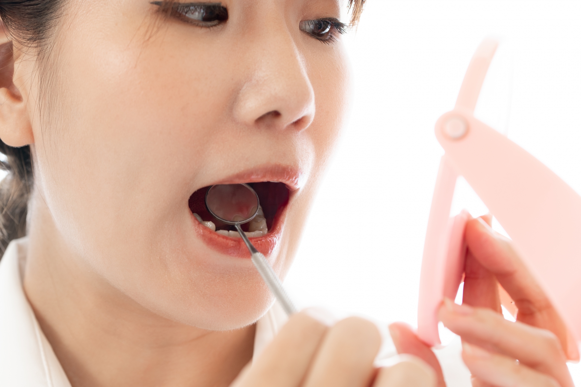 デンタルミラーで口の中と歯を見る女性