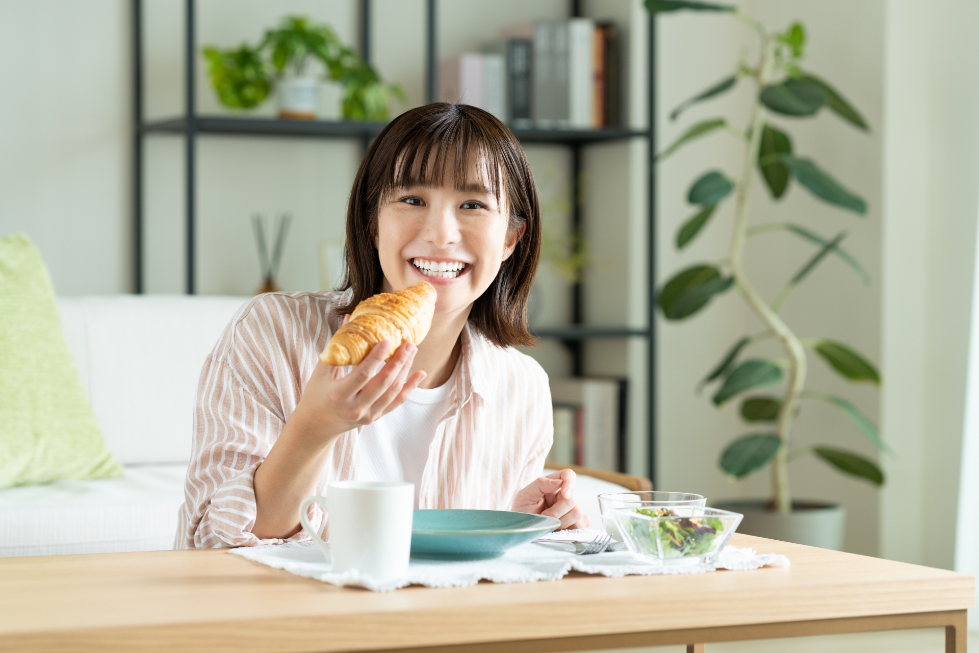 クロワッサンを食べる若い女性