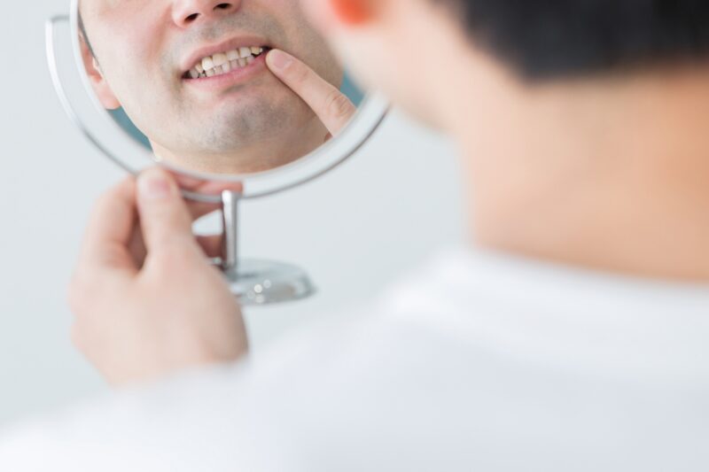 鏡で歯をチェックする男性